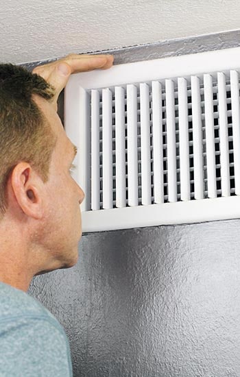 A man inspects an air vent
